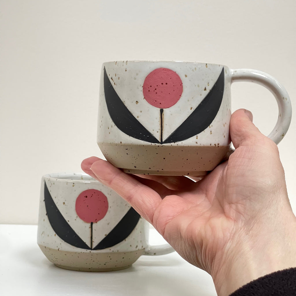 Get cozy with a warm cup, wheel thrown and decorated with a Scandinavian aesthetic. This substantial beauty of a mug comes in 14oz to hold your favorite beverage or soup. We love the pop of color with a flower pattern in a pink palette.