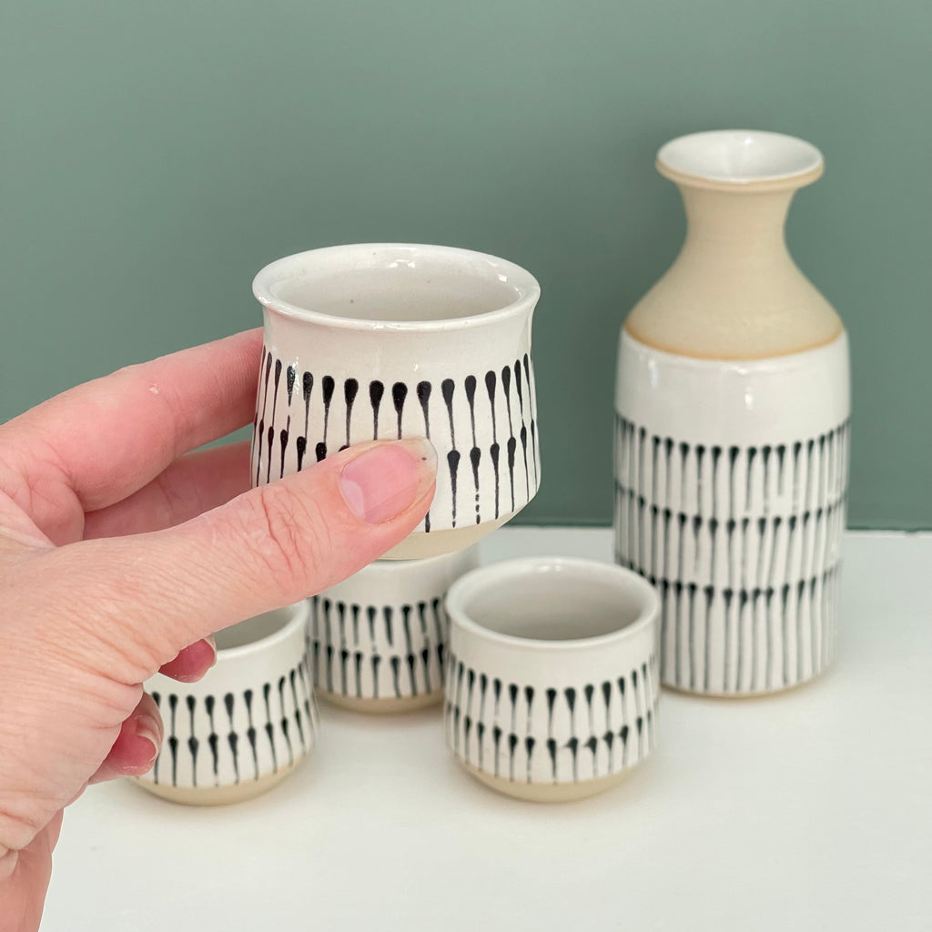 Handmade sake cups or espresso cups, with different decorative techniques. 1. teardrop pattern using black underglaze on top of the white glaze. Shown with coordinating sake carafe