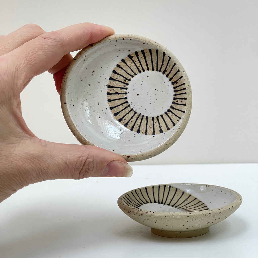 These hand decorated petite dishes are hand thrown on the wheel and features designer Judith Lemmens' Scandinavian-inspired folk art. This pattern is ‘Radial Circle’ design, using white underglaze on exposed clay.