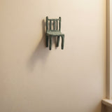 Small hanging blue ceramic sculpture of a chair on a living room wall