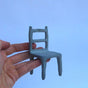 Small ceramic blue chair held in a hand 
