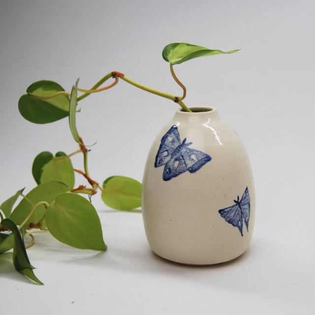 Small white vase with blue watercolor moth designs with green ivy