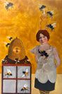 A woman with bees and a beehive on an orange honey-colored background