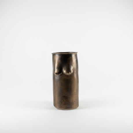 Bronze vase with breast forms on a plain background