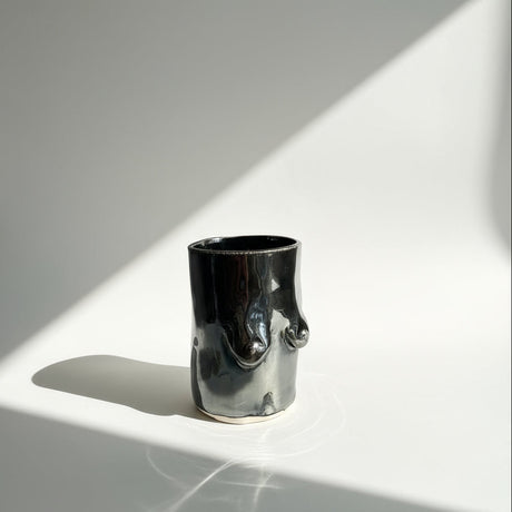 Shiny chrome glazed tittie cup or vase on a white background