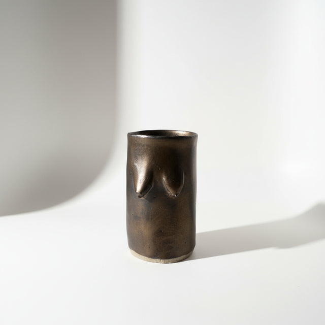 Bronze glazed tiddie cup or vase on a white background