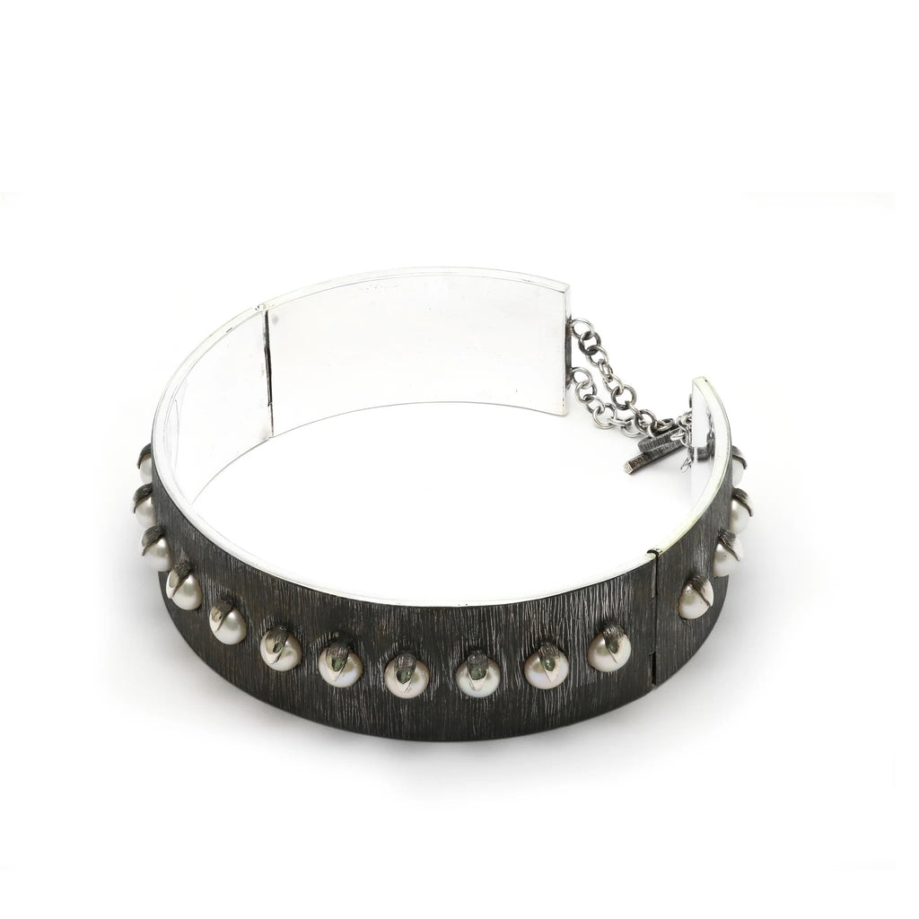 Top view of pearls collar or choker necklace. Claws of gleaming silver capture a collection of pearls embedded within the body of an etched silver necklace. This domination collar is the edgiest modernization of pearls.