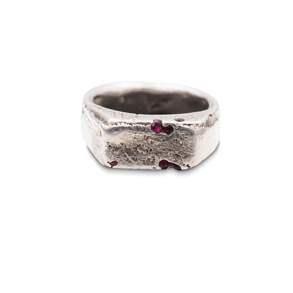 A signet ring made from hand poured molten silver that is sand cast in a mould with natural ruby gems. 