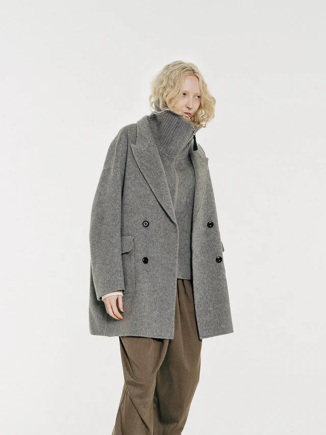 Sloane is a two-piece layering outerwear set pairing a structured heather gray double-breasted coat with a detachable high-neck vest insert. By Mute by JL out of New York City and shown on model. 