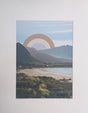 Collage landscape with mountains, ocean, and a cut paper sun in the sky.