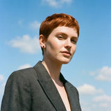 Female with short red hair wearing a grey blazer and garnet 3 prong martini stud earrings