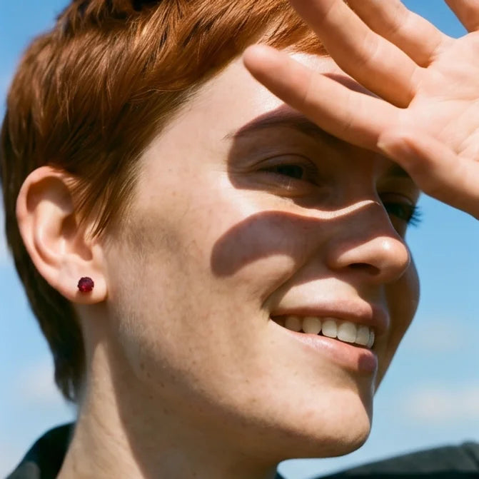 Close up of female model with short red hair wearing garnet 3 prong martini stud earrings