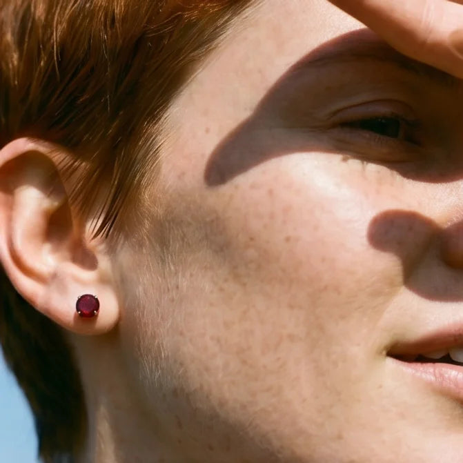Close up of female with short red hair wearing garnet 3 prong martini stud earrings