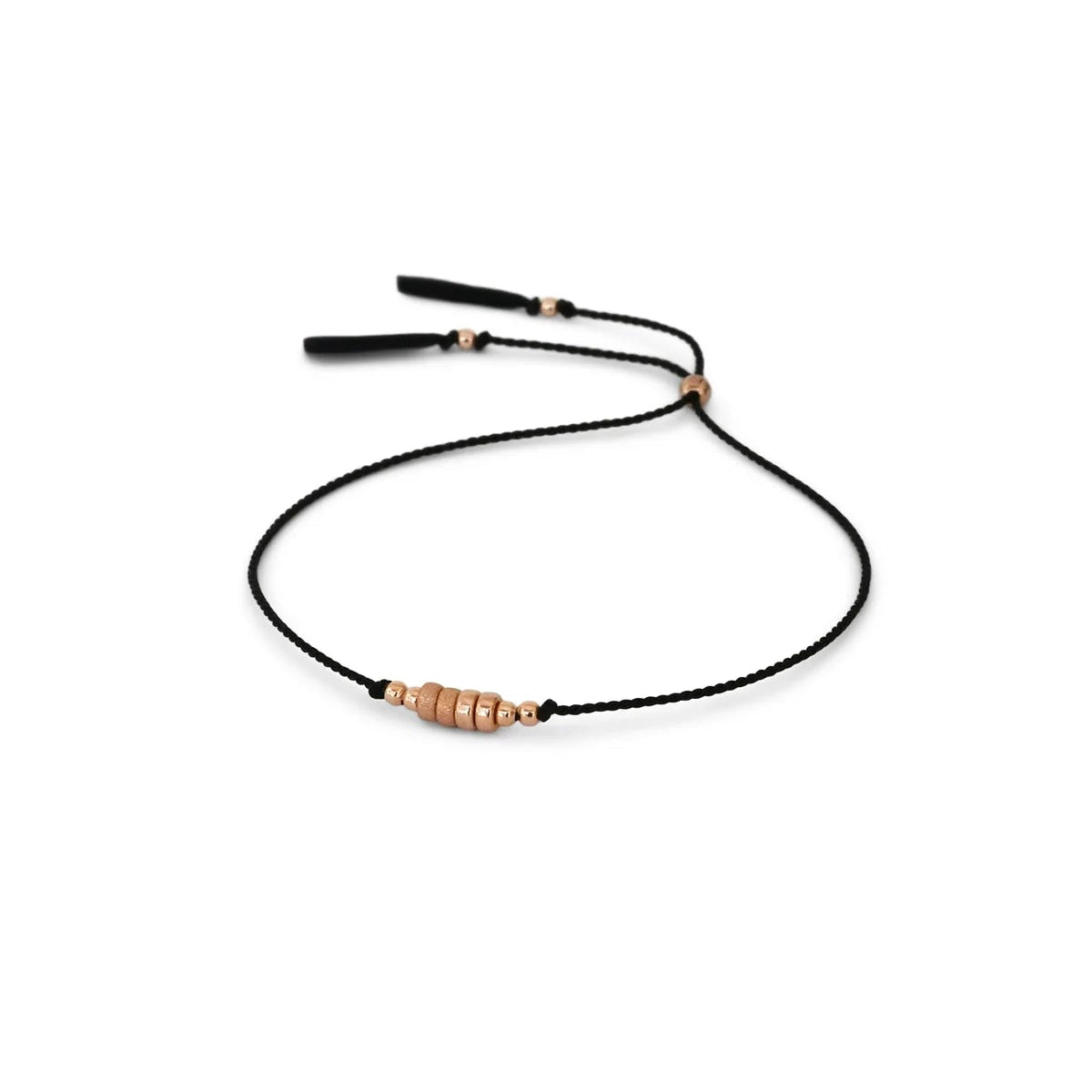 A delicate black csilk ord bracelet featuring a central cluster of small rose gold beads and adjustable black tassel ends, displayed on a clean white background.