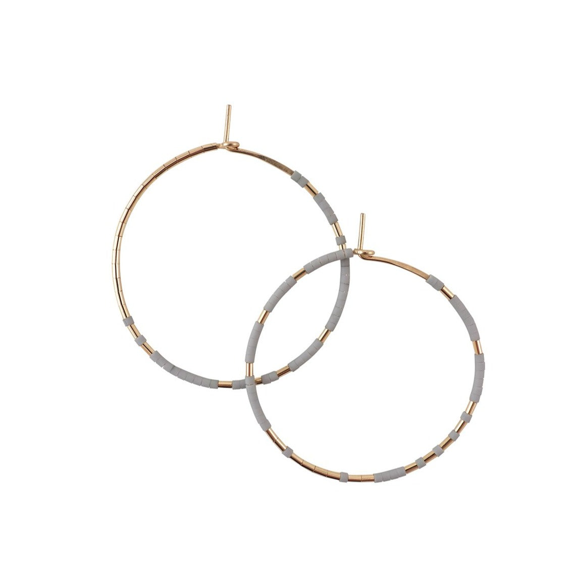 With Abacus Row's Pan Hoops, designer Christine Trac showcases an asymmetrical design of unexpected patterning of gold among matte glass beads. A medium grey tone.