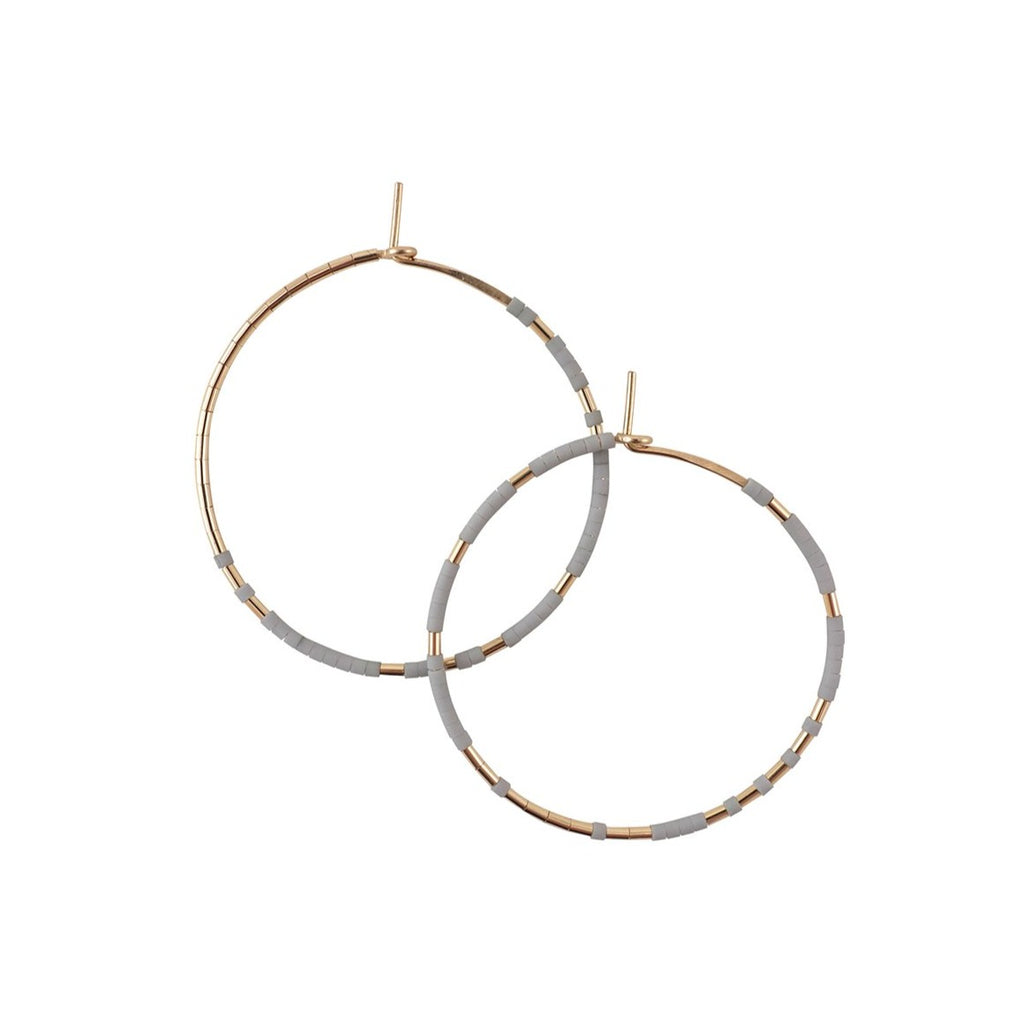 With Abacus Row's Pan Hoops, designer Christine Trac showcases an asymmetrical design of unexpected patterning of gold among matte glass beads. A medium grey tone.