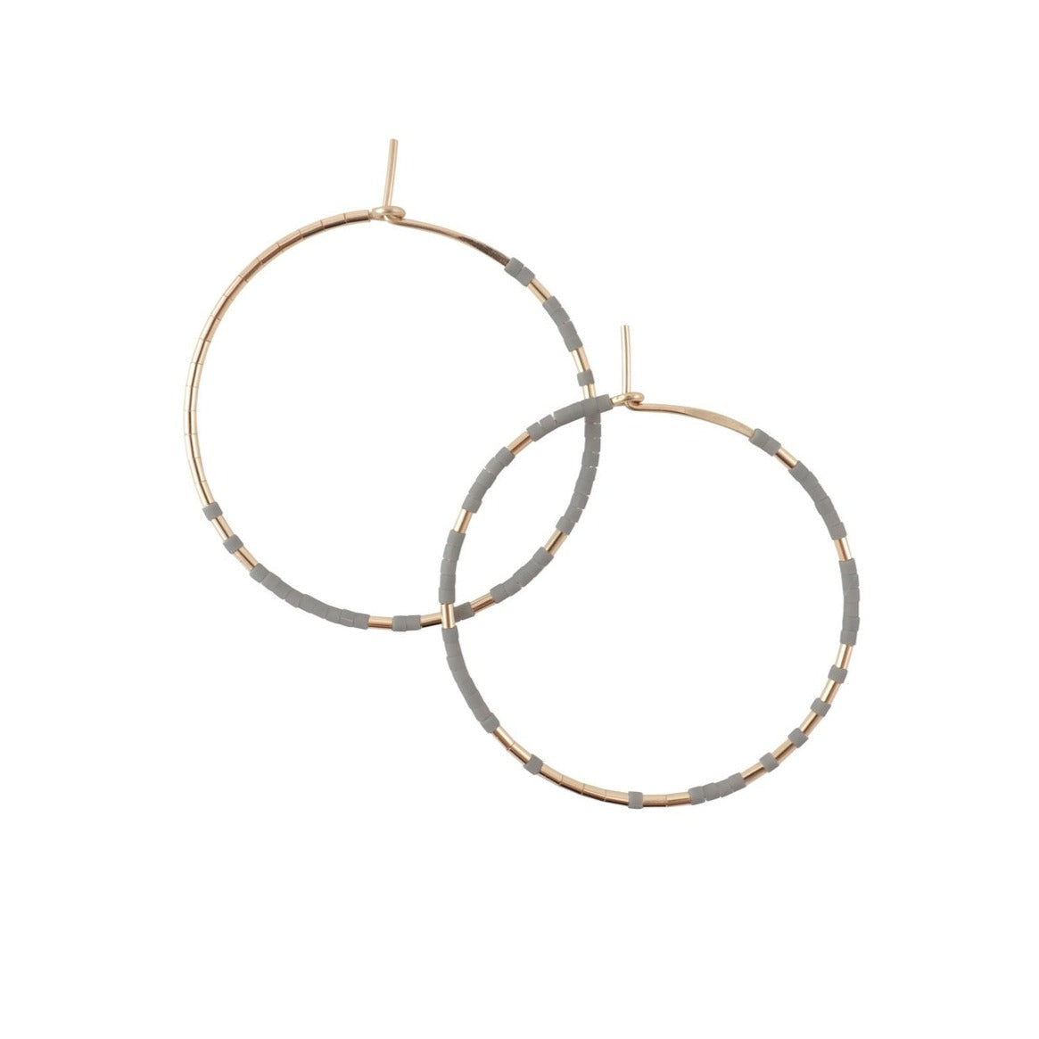 With Abacus Row's Pan Hoops, designer Christine Trac showcases an asymmetrical design of unexpected patterning of gold among matte glass beads. A cement grey tone.