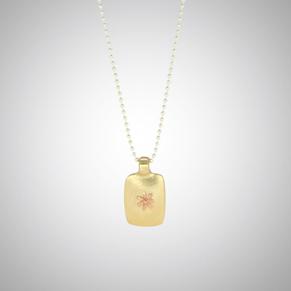 Jeffrey reimagined the classic dog tag into a modern canvas, both refined and a bit edgy. He loves mixing metals and embellished this 14k yellow gold dog tag with a contrasting 14K rose gold tiny flower charm