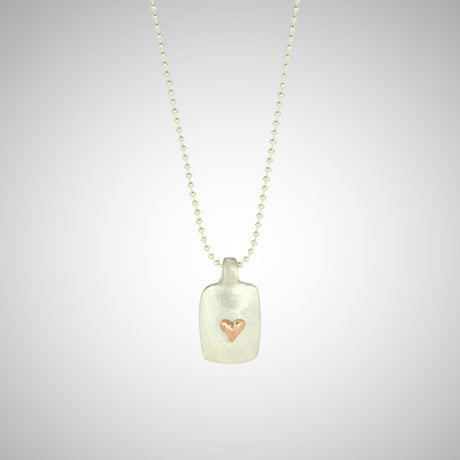 Jeffrey reimagined the classic dog tag into a modern canvas, both refined and a bit edgy. He loves mixing metals and embellished this sterling silver dog tag with a contrasting 14K rose gold tiny heart charm.