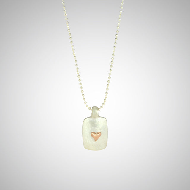 Jeffrey reimagined the classic dog tag into a modern canvas, both refined and a bit edgy. He loves mixing metals and embellished this sterling silver dog tag with a contrasting 14K rose gold tiny heart charm.