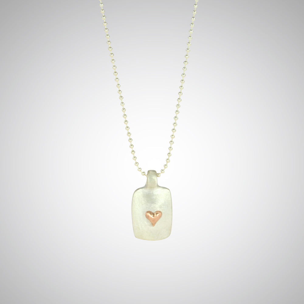 Jeffrey reimagined the classic dog tag into a modern canvas, both refined and a bit edgy. He loves mixing metals and embellished this sterling silver dog tag with a contrasting 14K rose gold tiny heart charm.