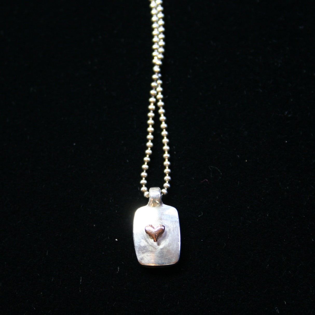 Jeffrey reimagined the classic dog tag into a modern canvas, both refined and a bit edgy. He loves mixing metals and embellished this sterling silver dog tag with a contrasting 14K rose gold tiny heart charm.