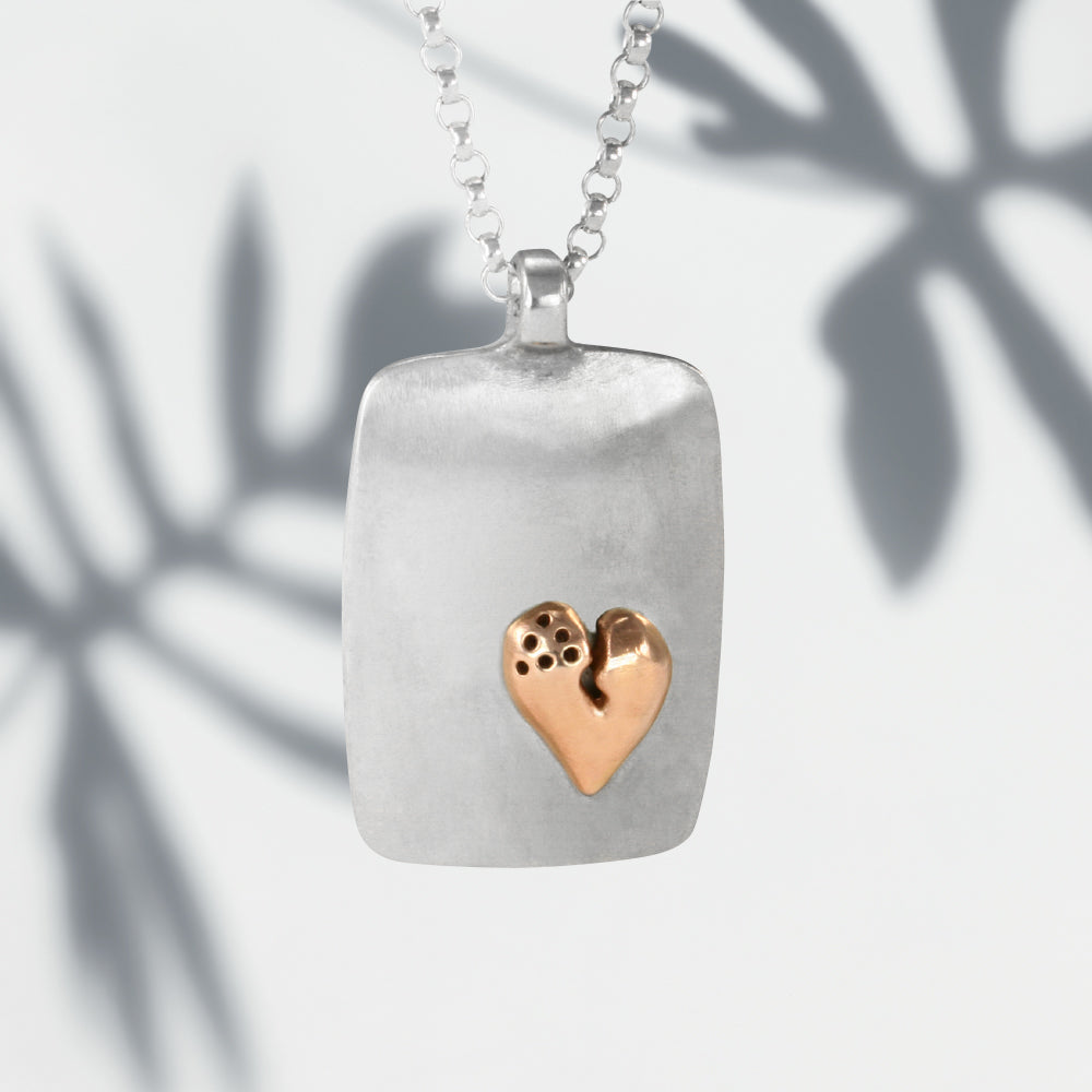Jeffrey reimagined the classic dog tag into a modern canvas, both refined and a bit edgy. He loves mixing metals and adorned this large sterling silver dog tag with a contrasting 14K rose gold healed heart pendant from his signature collection. 