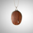 Jeffrey expands his wood collection with a stunning statement necklace using reclaimed wood, gorgeously reused. He cuts the wood to best feature the beauty of the graph lines, from creamy brown to pink-brown. He also makes a setting for a single diamond and pins it through the wood, while setting the two in a large oval sterling setting on chain. 