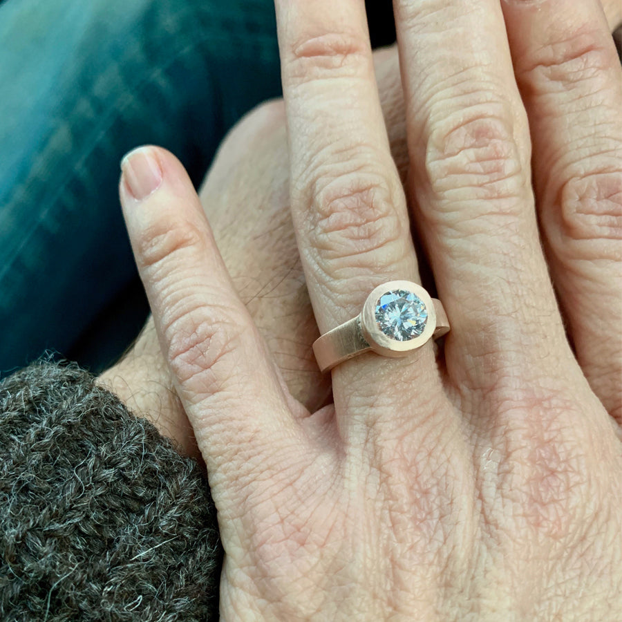 The custom engagement ring designed by Jeffrey Levin has been carved in wax, cast in rose gold and features and stunning diamond. Shown on bride's hand.