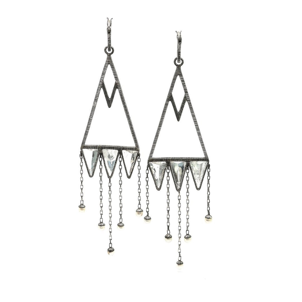 These are Mariella's stunning version of chandelier earrings. Rough-hewn rock crystals are cased in etched and oxidized silver to create capture points for hanging pearl raindrops. Front view.