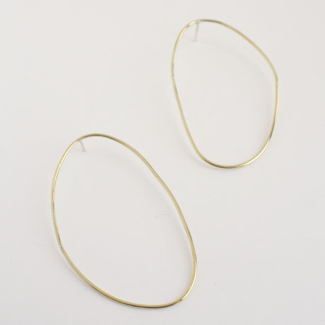 Asymmetrical oval olive-shaped brass earring hoops boast a sophisticated yet modern aesthetic. 