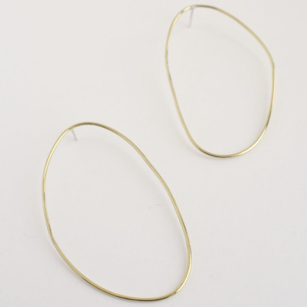 Asymmetrical oval olive-shaped brass earring hoops boast a sophisticated yet modern aesthetic. 