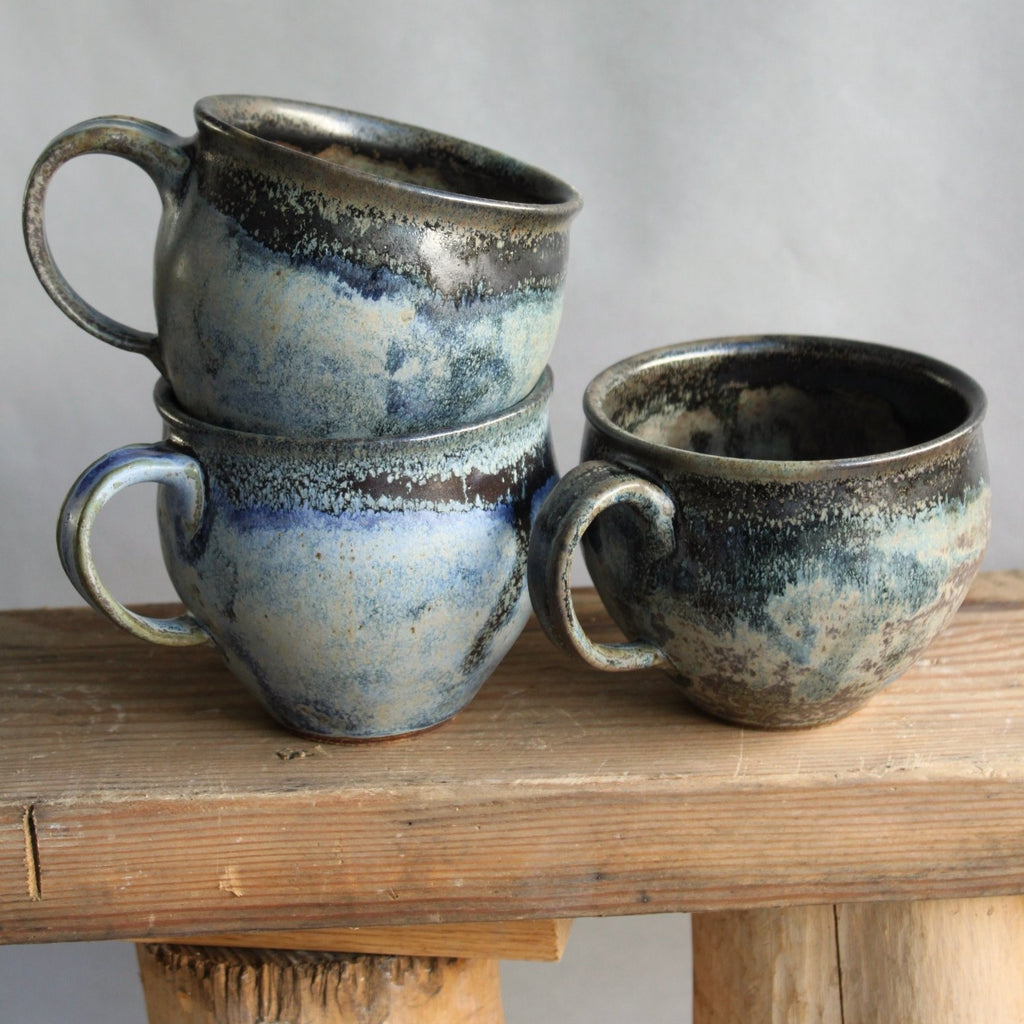 Sisters Ceramics stoneware belly mugs. Rounded and tapered to feel nice in the hand, they have a one-finger handle. We love this variable blue glaze, like the ocean in your palm.